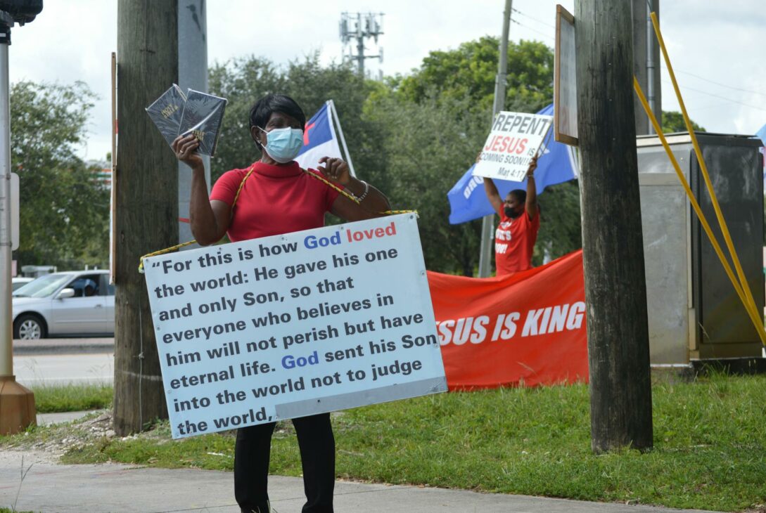 woman in medical mask and board with script on street