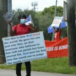 woman in medical mask and board with script on street