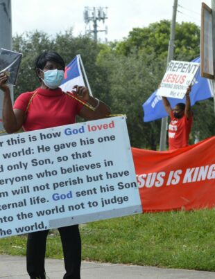 woman in medical mask and board with script on street