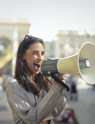 cheerful young woman screaming into megaphone