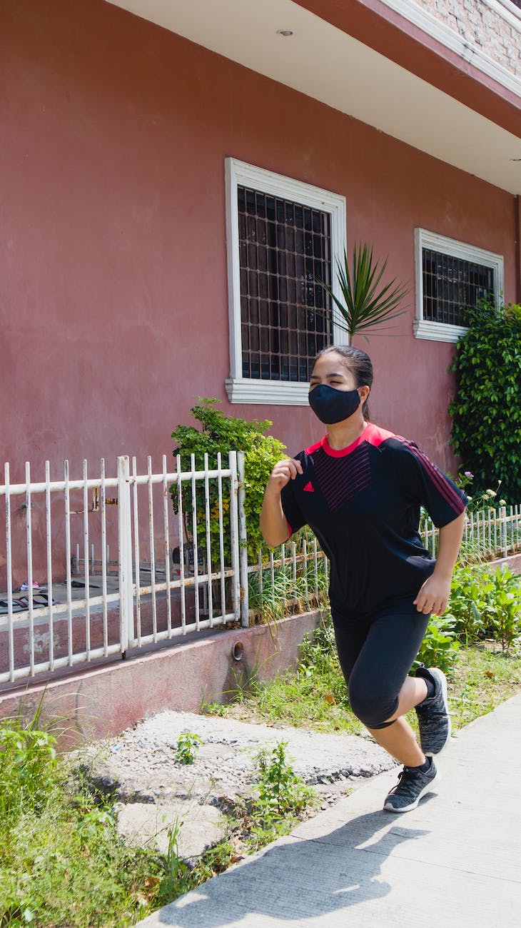 photo of woman jogging beside building during daytime