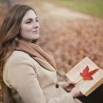 young woman with book in autumn park