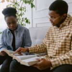 woman in blue dress shirt sitting beside man in white and brown plaid button up shirt