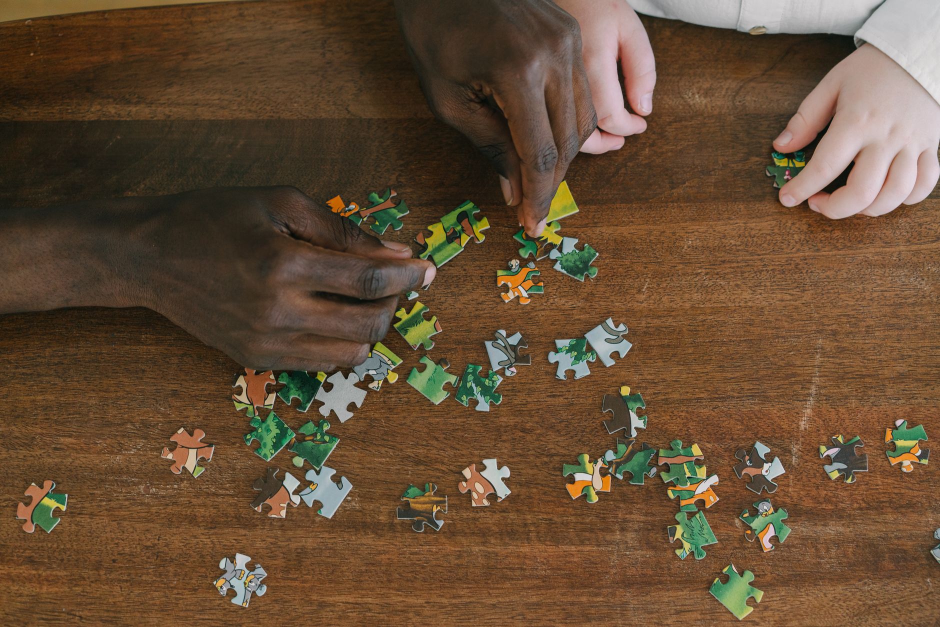 close up shot of two people playing jigsaw puzzle on a wooden surface